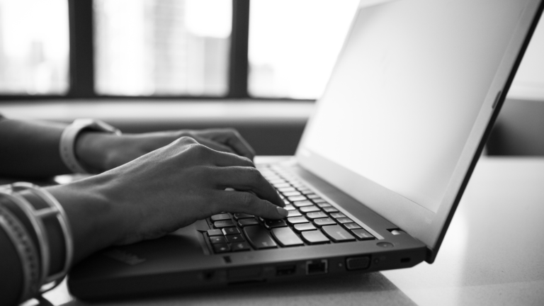 Woman's hands typing on a laptop computer in black and white