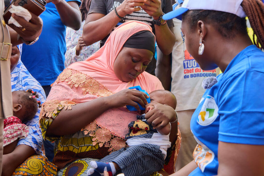 Mother Cisse Maman administers the first monthly dose of anti-malarial medicine to her child under the supervision of SMC campaign volunteer Kone Eve taitcha during the SMC campaign kick off on July 27th. Photo credit: Soumahoro Fabrice
